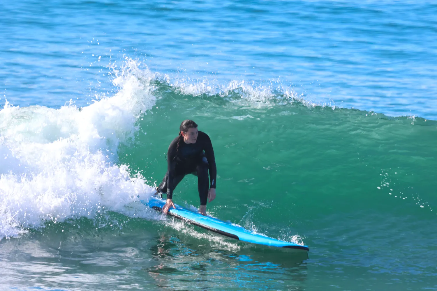 Woman surfer rides backside on wave at Corky Carroll's Surf School